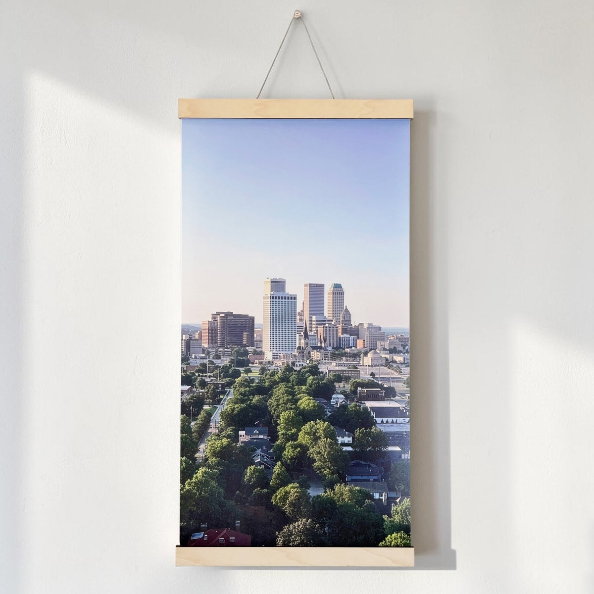 Tulsa skyline canvas wall hanging displayed above a wood console, showing an elevated view of downtown Tulsa and surrounding green neighborhoods as Oklahoma home decor