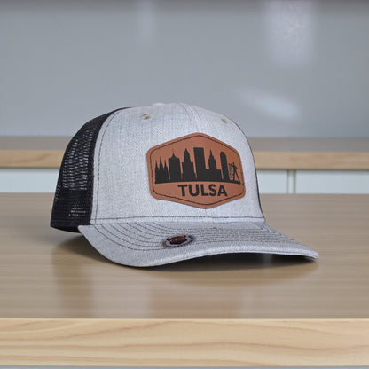 Angled view of Tulsa skyline trucker hat with leatherette patch, curved bill snapback hat designed as Tulsa souvenir