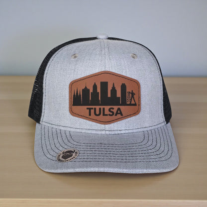 Close up of Tulsa skyline leatherette patch on trucker hat, engraved Tulsa city design with clean stitched edge