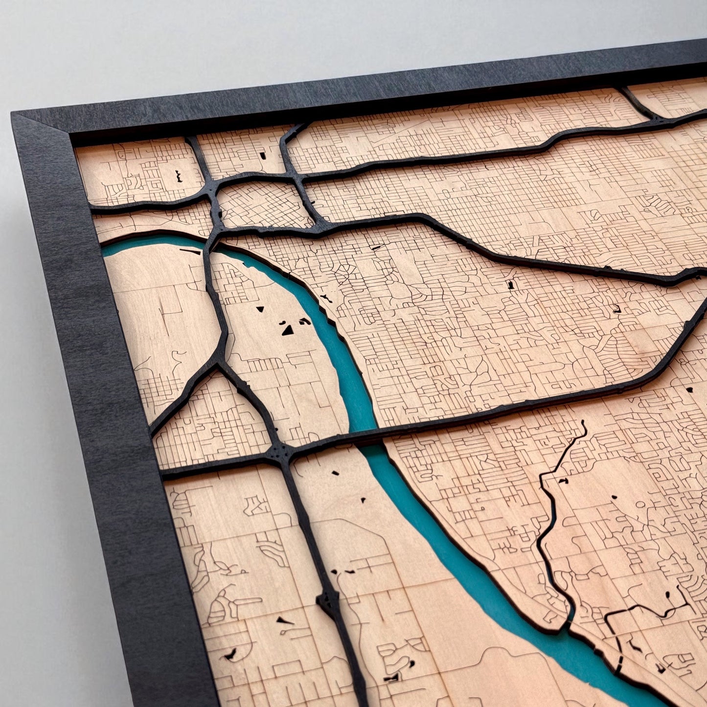 Close up of painted blue river on Tulsa wooden city map, layered wood design showing river and surrounding streets