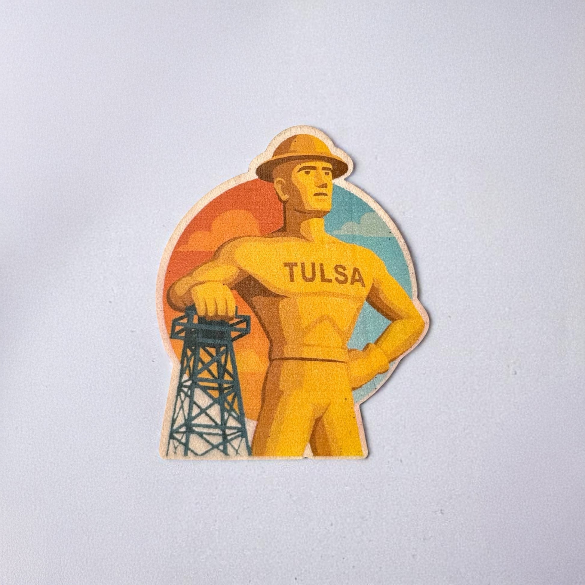 Illustrated Tulsa Golden Driller wood sticker featuring the iconic oilman against a vibrant sunset background, ideal for decorating journals, lockers, or dry surfaces indoors.