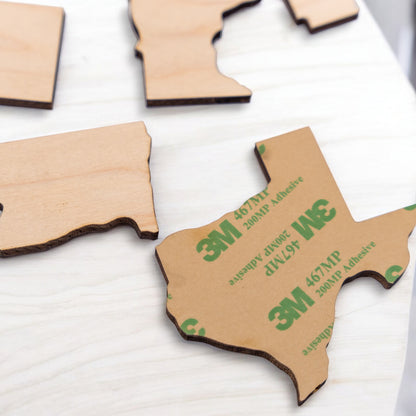 Wooden USA state pieces showing peel off adhesive backing for permanent placement