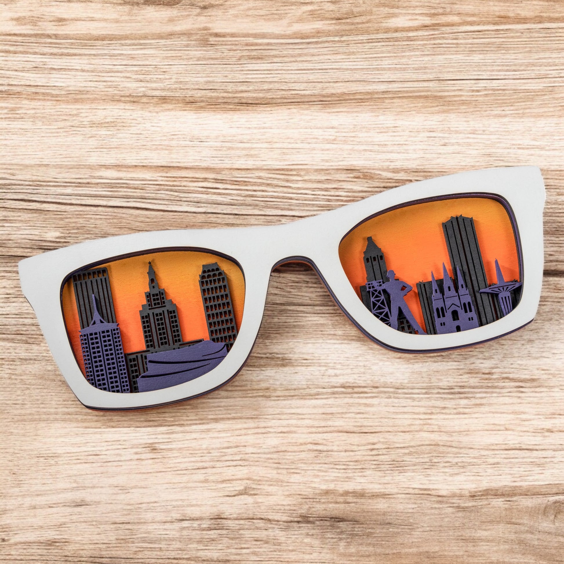 White frame Tulsa skyline sunglasses wooden decor with layered city skyline and orange yellow sunset background